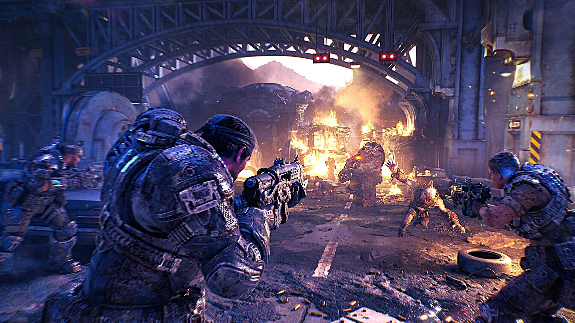 Armored sci-fi soldiers take cover beneath a steel bridge, firing toward enemies amid flames, smoke, and wreckage in a tense urban battle.